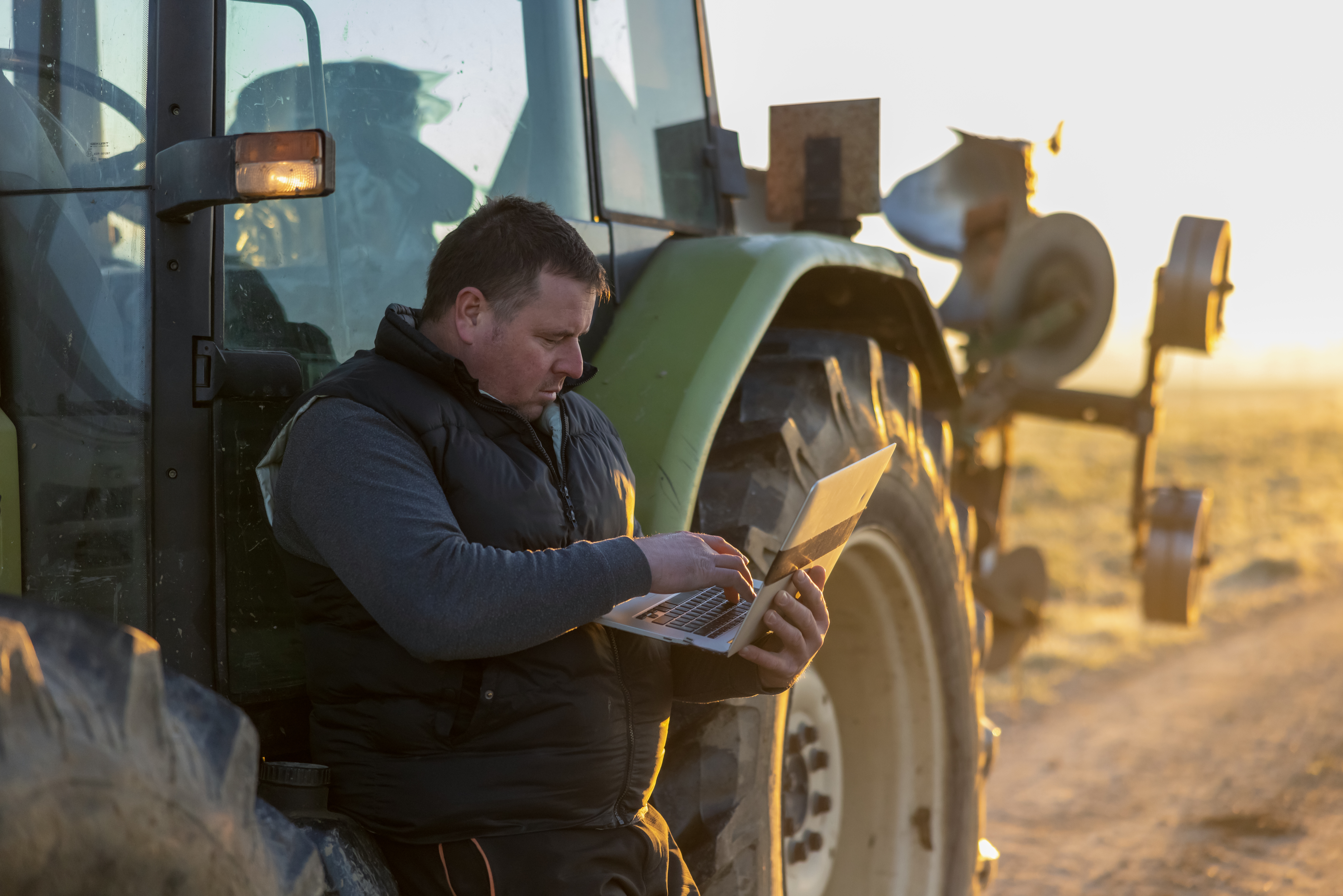 Farmer Using Laptop By Tractor